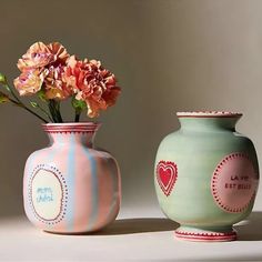 two vases with flowers in them sitting next to each other