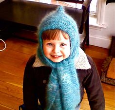 a young child wearing a blue knitted hat and scarf on top of a wooden floor