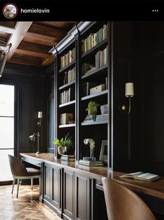 a home office with black walls and wooden flooring, built in bookshelves