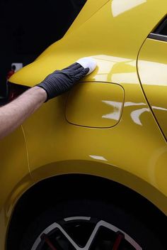 a man waxing the side of a yellow car