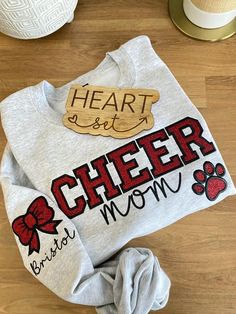 ** Please read before buying **  Personalized Embroidered Cheer Mom Shirt with glitter HTV applique. Fit: Unisex, Fits loose/relaxed Sizing: S,M,L,XL,2XL Material: 50% Cotton, 50% Polyester Embroidery Details: "Cheer Mom" centered across the chest and paw print off centered under the "R" Bow and Child name on right shoulder sleeve PROCESSING/TURNAROUND TIME: -Processing/Turn around times may vary. Please check the estimated ship/delivery times. -Processing/Turn around time DOES NOT include shipping time. Cheer Shirts For Moms, Cheer Sister Shirts, Cheer Mom Shirt, Cheer Shirt Ideas, Cheer Mom Sweatshirt Ideas, Cheer Mom Shirt Ideas, Peewee Cheer, Basketball Shirt Designs, Cheerleading Shirts