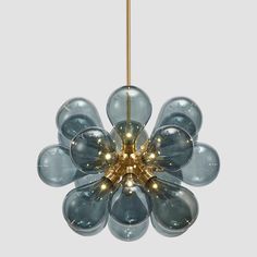 a blue flower shaped chandelier hanging from a gold colored ceiling fixture with lights in the center