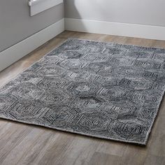 an area rug in the corner of a room with wood flooring and white walls