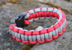 a red and grey paracorte bracelet on top of a rock