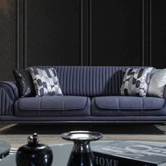 a blue couch sitting in front of a table with two vases on top of it