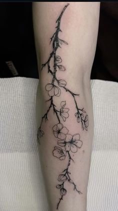 a tattoo on the leg of a woman with flowers growing out of it's side