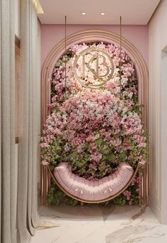 pink flowers and greenery decorate the entrance to a room with a circular mirror on the wall