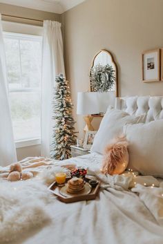 a white bed topped with pillows next to a window covered in christmas decorations and lights