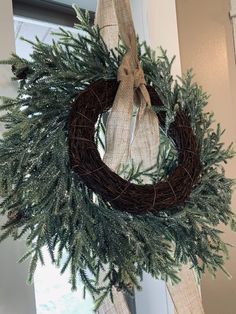 a wreath hanging on the front door with burlock and pine needles attached to it