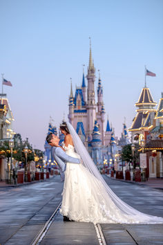 a bride and groom kissing in front of cinderella's castle at disney world during their wedding day