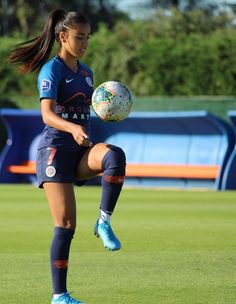 a female soccer player in action on the field with a ball and her leg up