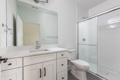 a bathroom with a toilet, sink and shower stall is pictured in this image from the front view