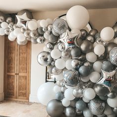 a room filled with lots of silver and white balloons hanging from the ceiling next to a doorway