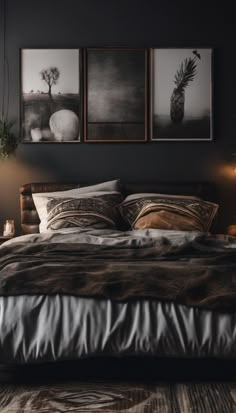 a bed with two pictures above it in a dark room next to a table lamp