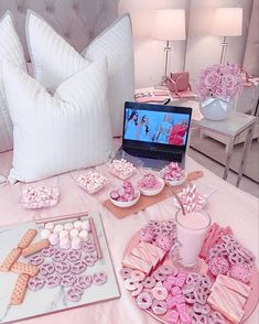 a laptop computer sitting on top of a bed next to desserts and marshmallows