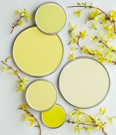 three paint cans with yellow and white paint sitting on top of each other next to flowers