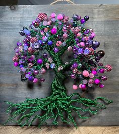 a tree made out of plastic beads on a wooden board