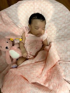 a baby sleeping on a pink blanket next to a teddy bear