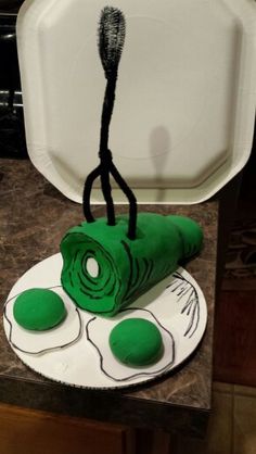 a cake made to look like a green thing on top of a white plate with black handles