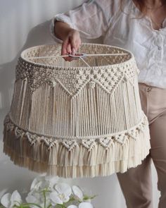 a woman is holding a lamp shade that has tassels and fringes on it