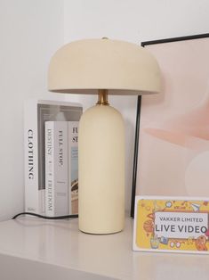 a white lamp sitting on top of a table next to a book case and a card