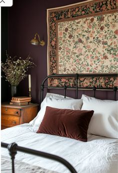 a bed with white sheets and pillows in front of a painting on the wall above it