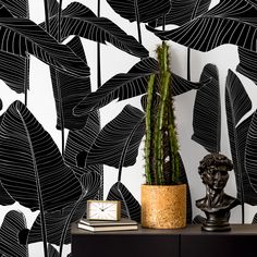 a black and white wallpaper with a plant in a gold vase next to it