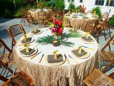 a table set up with place settings and flowers on it for an outdoor dinner party