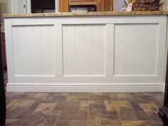 the kitchen counter is made out of wood and has white paneling on it's sides