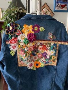 the back of a jacket with flowers on it and buttons attached to the front pocket