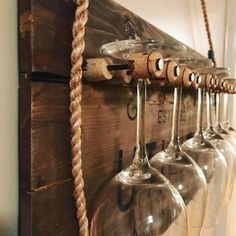 several wine glasses hanging on a wall with rope attached to the glass holders and hooks