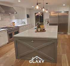 a large kitchen with an island and stainless steel appliances in the center, surrounded by white cabinets