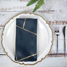 a white plate topped with a black napkin next to a fork and knife on top of a wooden table