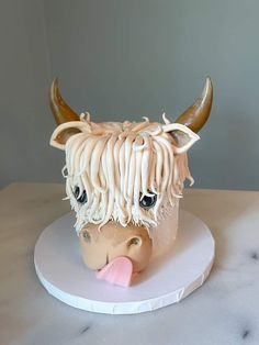 a ceramic cow head with long hair and large horns on a white plate sitting on a table