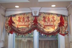 a kitchen window covered in red and gold curtains