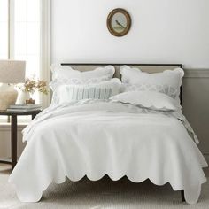 a bed with white linens and pillows in a bedroom next to a window,