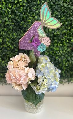 a vase filled with flowers and a number four shaped like a butterfly sitting on top of it