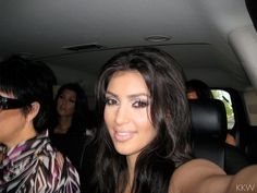 two women sitting in the back seat of a car with one woman taking a selfie