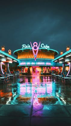 an outdoor cafe with tables and umbrellas lit up at night in front of it