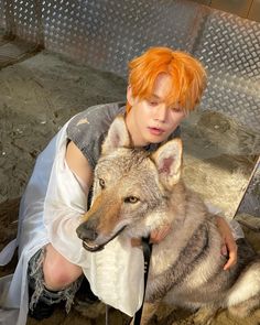 a woman with red hair is holding a wolf