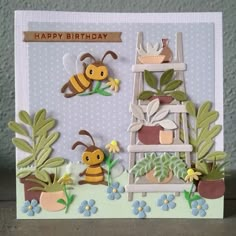 a handmade birthday card with two bees on a ladder and flowers in potted plants