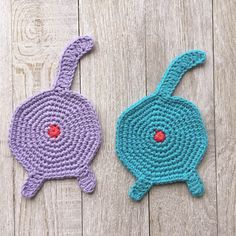 two crocheted coasters sitting on top of a wooden table next to each other