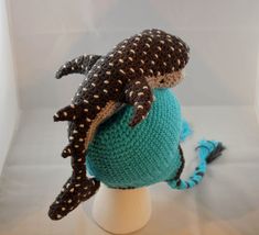 a crocheted turtle sitting on top of a blue and white ball in the shape of a hat