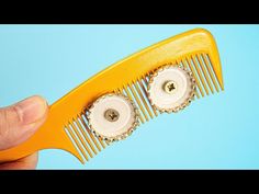 a person holding a yellow comb with two white buttons on the front and bottom of it