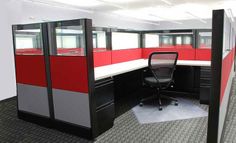 an office cubicle with red and grey walls, black chairs, and white desks