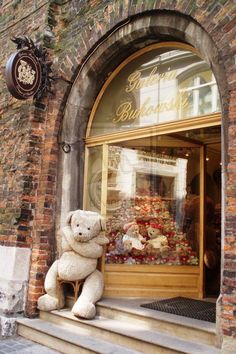 a teddy bear sitting on the steps in front of a store