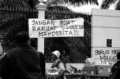 black and white photograph of people walking in front of a building with graffiti on it