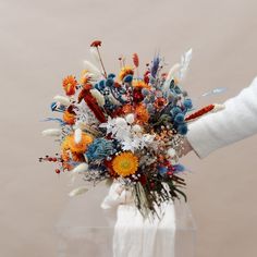 a person is holding a bouquet of flowers in their left hand and wearing a white sweater