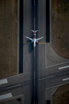 an airplane is flying low to the ground over some roads and fields, from above