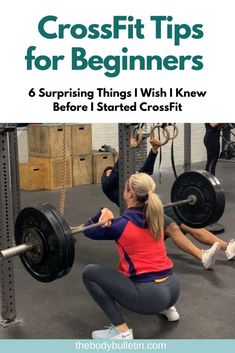 a woman squats on the ground while holding a barbell in front of her